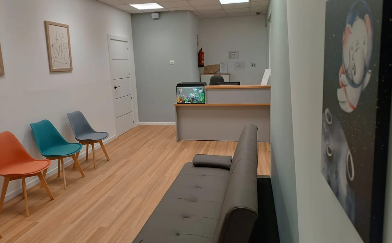 Sala de espera con sillas de colores, sofá y recepción